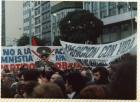 Pancarta de Aparición con vida junto a otra del Partido Obrero contra la amnistía en que aparece un monigote militar tachado